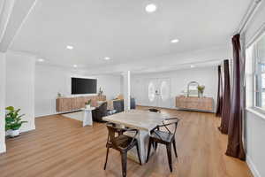 Dining area featuring light wood-type flooring, french doors, recessed lighting, healthy amount of natural light, and crown molding