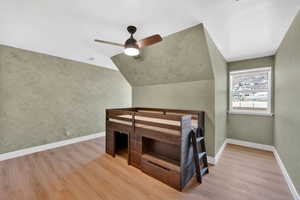 Unfurnished bedroom featuring light wood-style flooring, lofted ceiling, and ceiling fan