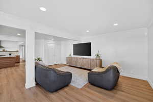 Living room featuring ornamental molding, light wood-style floors, and recessed lighting