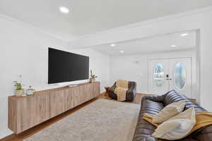 Living area featuring wood finished floors, crown molding, recessed lighting, french doors, and beamed ceiling