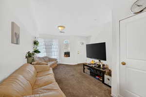 Living area featuring dark carpet and baseboards