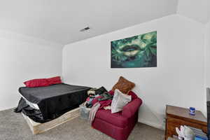 Bedroom with vaulted ceiling and carpet floors