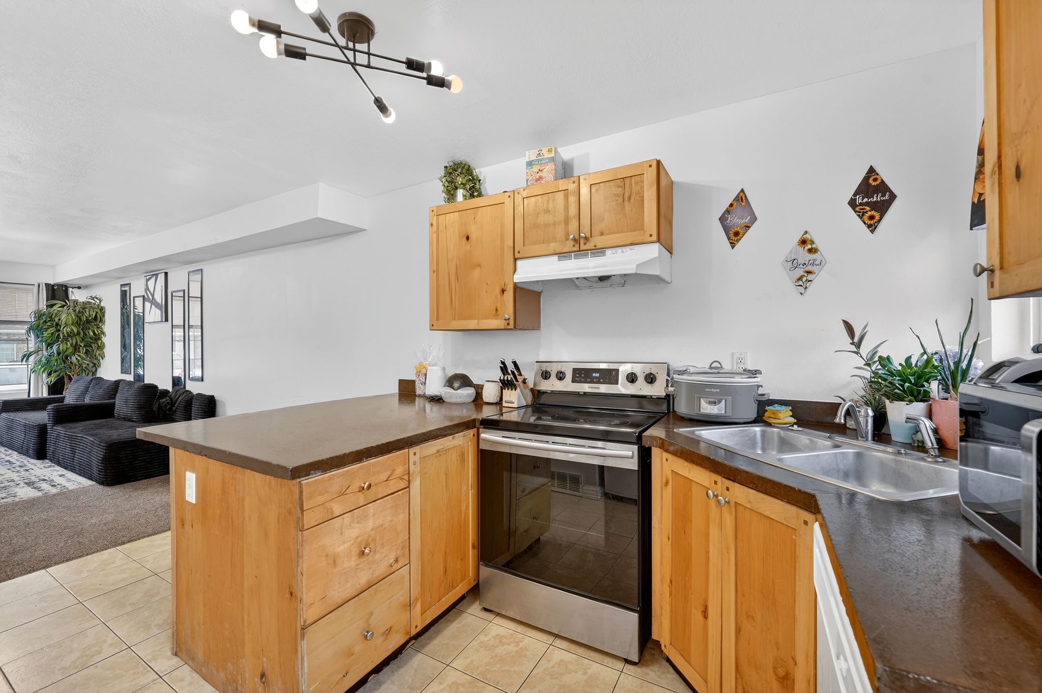 Kitchen with a peninsula, stainless steel appliances, open floor plan, and light tile patterned floors