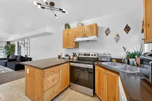 Kitchen with a peninsula, stainless steel appliances, open floor plan, and light tile patterned floors