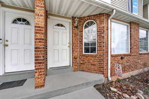 Doorway to property featuring brick siding and a porch