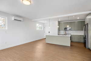 Kitchen featuring decorative backsplash, modern cabinets, a kitchen island with sink, stainless steel appliances, and hanging light fixtures