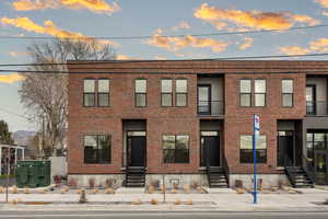 View of front of property featuring brick siding and a balcony