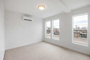 Unfurnished room with light carpet and a wall mounted mini split