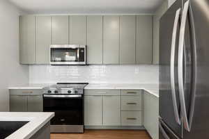 Kitchen with stainless steel appliances, backsplash, light stone countertops, modern cabinets, and a textured ceiling