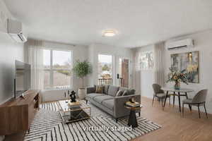 Living room featuring a textured ceiling, a wall mounted mini split, and light wood-style floors