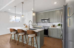 Kitchen featuring stainless steel appliances, a kitchen breakfast bar, an island with sink, pendant lighting, and tasteful backsplash