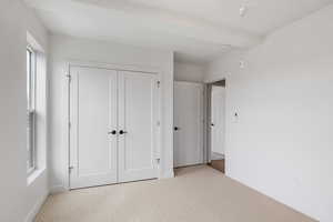 Unfurnished bedroom with light colored carpet and a closet