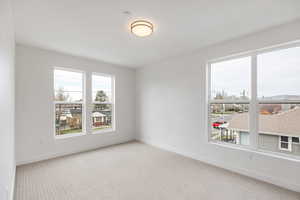 Unfurnished room with light colored carpet and baseboards