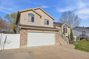 View of front of home with stone siding, a garage, driveway, stucco siding, and roof with shingles