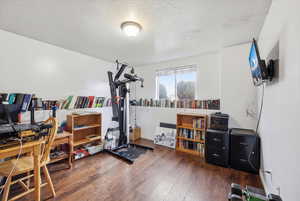 Exercise room featuring dark wood-style flooring and a textured ceiling