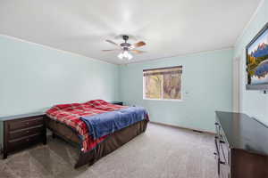 Carpeted bedroom with ornamental molding and a ceiling fan