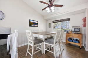 Dining space featuring dark wood-style flooring, a ceiling fan, and vaulted ceiling