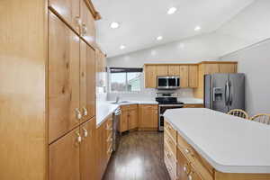 Kitchen with stainless steel appliances, lofted ceiling, light countertops, dark wood finished floors, and recessed lighting