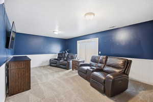 Cinema with wainscoting, light carpet, and a textured ceiling