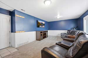 Living room featuring light carpet, a wainscoted wall, and light tile patterned flooring
