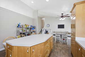 Kitchen featuring a ceiling fan, light countertops, dark wood-style flooring, lofted ceiling, and a center island