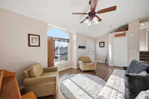 Living room featuring a ceiling fan, hardwood / wood-style floors, and vaulted ceiling