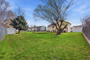 Fenced backyard featuring a trampoline and a shed