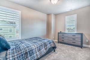 Bedroom with light colored carpet and a textured ceiling