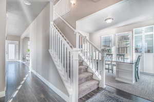 Stairs with hardwood / wood-style floors and a textured ceiling