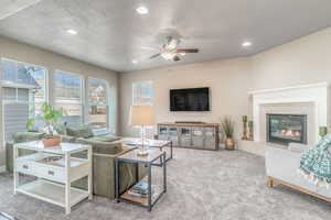 Living room with ceiling fan, carpet flooring, recessed lighting, a textured ceiling, and a tile fireplace