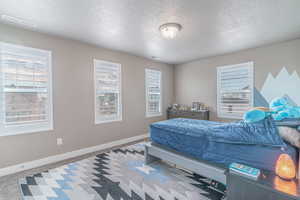 Bedroom with light colored carpet and a textured ceiling