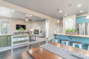 Dining area featuring dark wood-type flooring, a glass covered fireplace, recessed lighting, and a ceiling fan