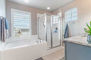 Bathroom featuring plenty of natural light, vanity, a stall shower, and light tile patterned flooring