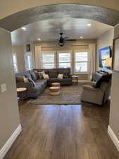 Living area with arched walkways, dark wood-style flooring, ceiling fan, healthy amount of natural light, and recessed lighting