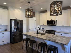 Kitchen with fridge with ice dispenser, hanging lights, white cabinets, and stainless steel gas stove