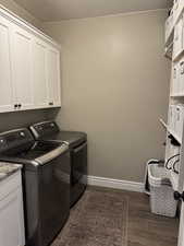 Laundry area with washing machine and clothes dryer, dark wood-style flooring, and cabinet space