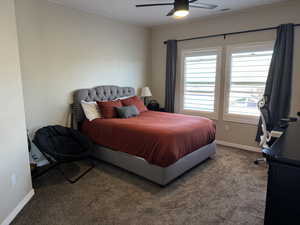 Bedroom with ceiling fan and dark colored carpet