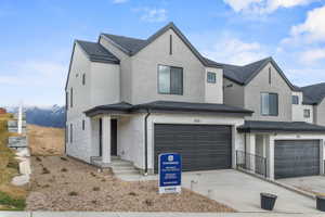 View of front of home featuring a garage, stone siding, concrete driveway, and stucco siding