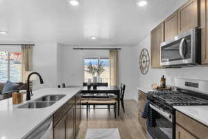 Kitchen featuring stainless steel appliances, light stone countertops, light wood-type flooring, open floor plan, and recessed lighting