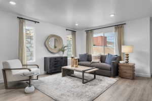 Living area with light wood finished floors and recessed lighting