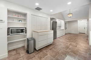 Walk in closet featuring lofted ceiling and stone finish flooring