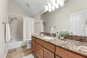 Full bathroom featuring vanity, shower / tub combo with curtain, and vaulted ceiling