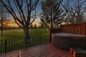 Deck at dusk featuring a hot tub