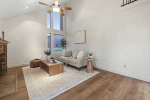 Living room featuring a brick fireplace, wood finished floors, a ceiling fan, and vaulted ceiling