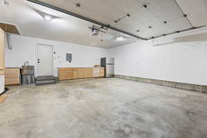 Garage featuring freestanding refrigerator and electric panel