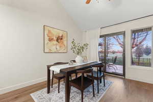 Dining area featuring light wood-style flooring, vaulted ceiling, ceiling fan, and a water view