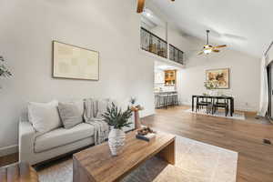 Living room with ceiling fan, wood finished floors, and lofted ceiling