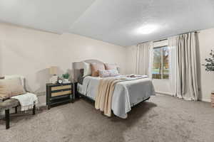 Bedroom with light colored carpet and a textured ceiling