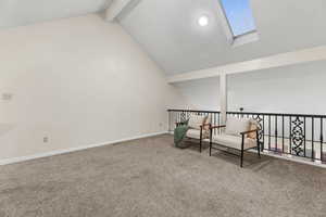 Living area with a skylight, beam ceiling, and carpet floors