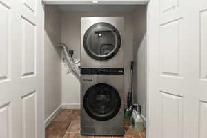 Laundry area featuring stacked washer and dryer and tile patterned flooring